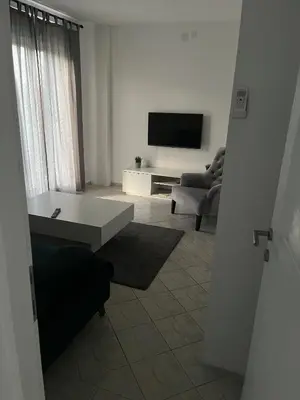 a white living room with a television and a couch at MAGIC M Apartment in Mali Mokri Lug