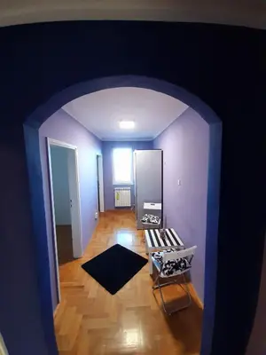 an empty living room with purple walls and wooden floors at Apartments best city place in Belgrade