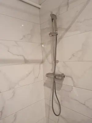 a shower with a hose in a white marble shower stall at Mosaic in Belgrade