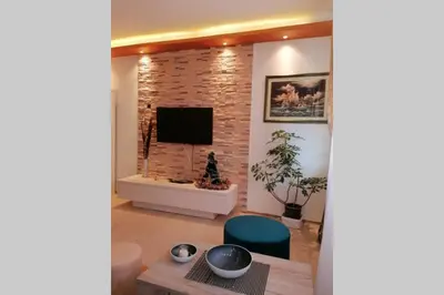 a living room with a television and a brick wall at Oasis felix apartment in Belgrade
