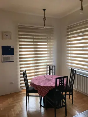a dining room with a table and chairs and windows at STIV, Voždovac, Stepa Stepanovic in Voždovac