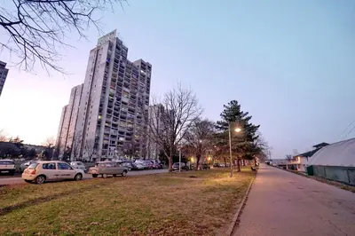 a city street with cars parked in front of a tall building at Apartman Lido in Belgrade