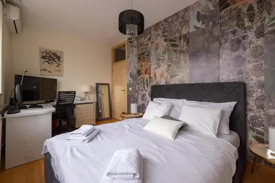 a bedroom with a large white bed and a desk at La Maison Panoramique Belgrade in Belgrade