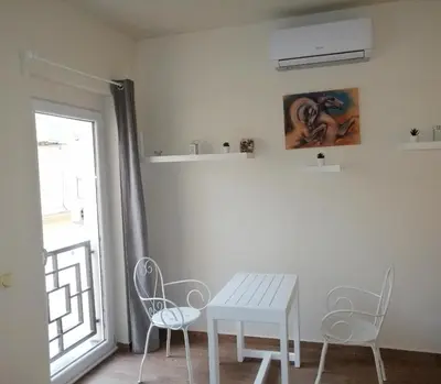 a white table and chairs in a room with a window at Retro apartment in Zemun
