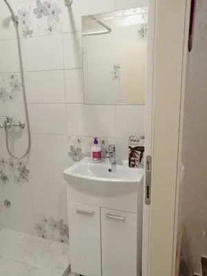 a white bathroom with a sink and a shower at Retro apartment in Zemun