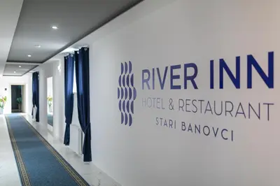 a sign for the river inn hotel and restaurant on a wall at River Inn in Stari Banovci