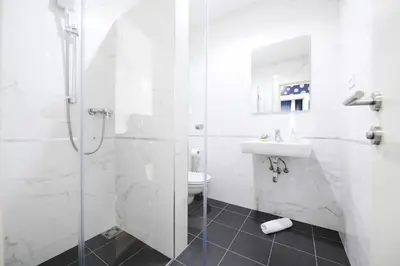 a white bathroom with a shower and a sink at River Inn in Stari Banovci
