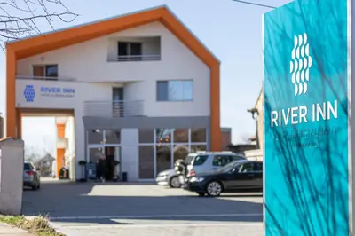 a building with cars parked in a parking lot at River Inn in Stari Banovci