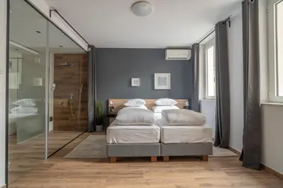 a bedroom with a bed and a glass shower at HostGost Selected Suites - Botanical Garden in Belgrade
