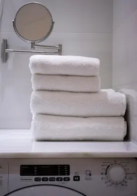 a stack of towels sitting on top of a washing machine at HostGost Selected Suites - Botanical Garden in Belgrade