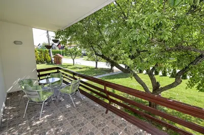 a balcony with a table and chairs and a tree at Apartman DORA in Arandjelovac