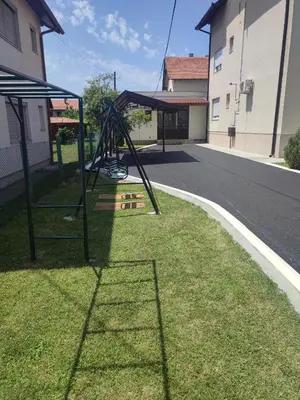 a swing set in the grass next to a street at Apartman DORA in Arandjelovac
