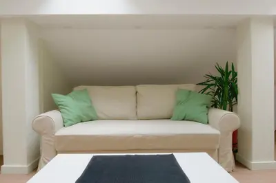 a white couch with two green pillows on it at VUKAJLO apartment Belgrade in Belgrade