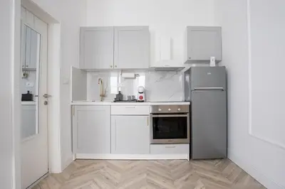 a kitchen with white cabinets and a stainless steel refrigerator at Etoile City Center Apartments- Obilicev venac in Belgrade
