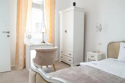 a white bedroom with a bed and a chair at Etoile City Center Apartments- Obilicev venac in Belgrade