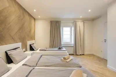 two beds in a large room with wooden floors at Belgrade Old Town Apartment in Belgrade