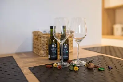 two wine glasses on a table with bottles of wine at Belgrade Old Town Apartment in Belgrade
