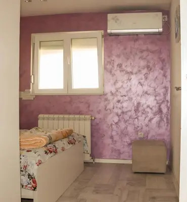 a bedroom with a bed and a pink wall at Juventas37 in Belgrade