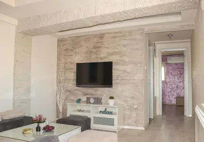 a living room with a tv on a stone wall at Juventas37 in Belgrade