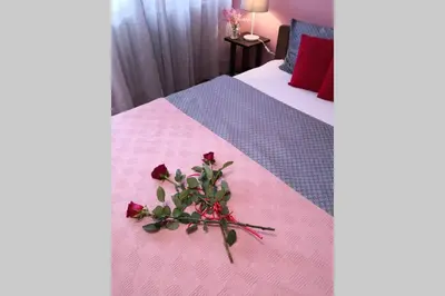 a room with two beds with a pink blanket and a flower arrangement at Studio Prim in Belgrade