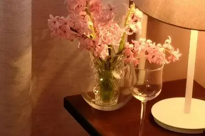 a vase of pink flowers on a table with a wine glass at Studio Prim in Belgrade