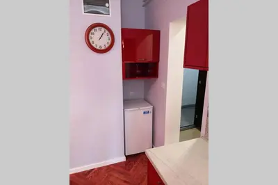 a kitchen with a refrigerator and a clock on the wall at Studio Prim in Belgrade
