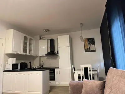 a kitchen with white cabinets and a table and chairs at Royal Residence Apartmani in Pančevo