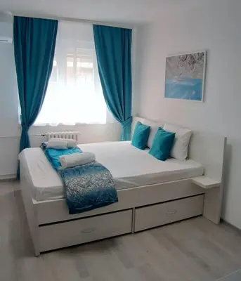 a bedroom with a large bed with blue curtains at Sarajevska Studio & Apartment in Belgrade