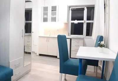 a kitchen with a table and blue chairs at Sarajevska Studio & Apartment in Belgrade