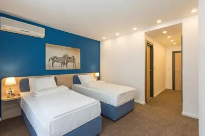 two beds in a hotel room with blue walls at Premium Crown Suites in Belgrade
