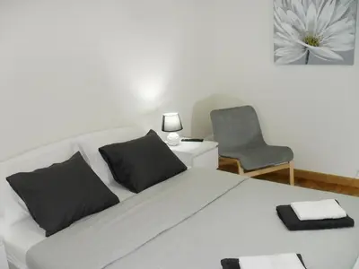 a white bed with black pillows and a chair at Belgrade Waterfront Lux 2 in Belgrade