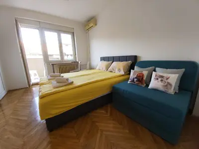 a bedroom with a large bed with yellow and blue sheets at Studio 17 in Belgrade