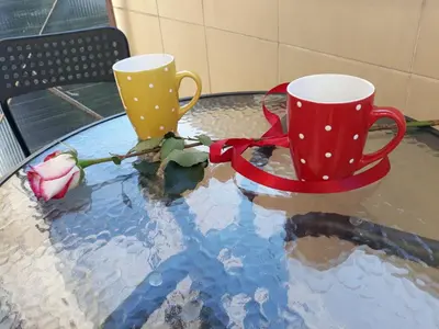 two coffee cups sitting on a glass table at Studio 17 in Belgrade