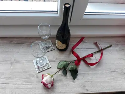 a bottle of wine and two wine glasses and a rose at Studio 17 in Belgrade
