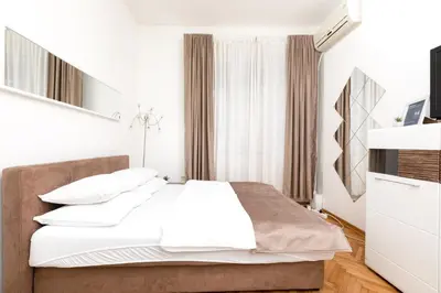 a bedroom with a bed with white sheets and pillows at 1st Belgrade Apartment in Belgrade