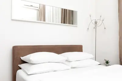 a bed with white pillows and a mirror above it at 1st Belgrade Apartment in Belgrade