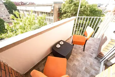 an apartment balcony with orange chairs and a table at Ahoy Belgrade Luxury Apartment in Belgrade
