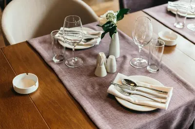 a table with plates and glasses and a vase of flowers at Central Point Hotel Beograd in Belgrade