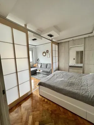 a bedroom with a bed and a living room at Comfortable apartment in city hub in Belgrade