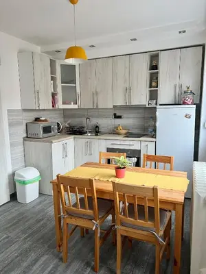 a kitchen with a wooden table with chairs and a refrigerator at Comfortable apartment in city hub in Belgrade