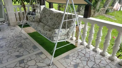 a porch swing on the front porch of a house at VILA PEKEČ in Mala Moštanica