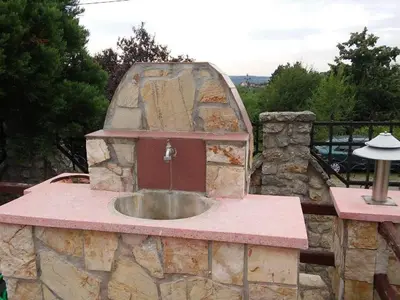 a stone kitchen with a sink on a patio at VILA PEKEČ in Mala Moštanica