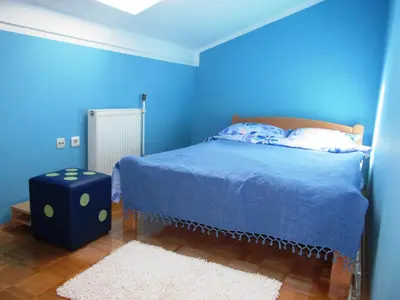 a blue bedroom with a bed and a white rug at Apartman 23 in Lazarevac