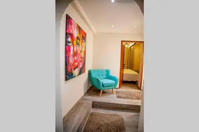 a hallway with a blue chair and a bedroom at Colorway Apartment in Belgrade
