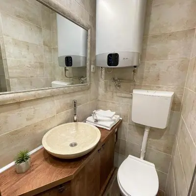 a bathroom with a sink and a toilet and a mirror at Colorway Apartment in Belgrade