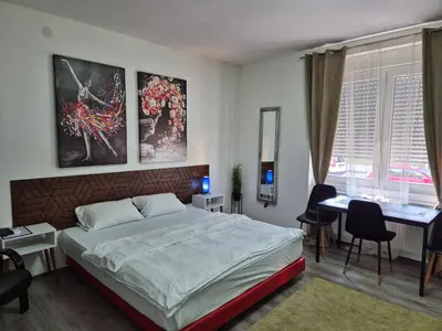 a bedroom with a bed and a table and a desk at Rooms Villa Luigi in Pančevo