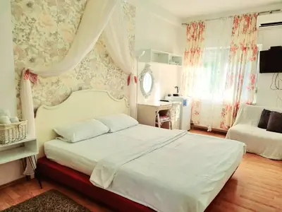 a bedroom with a white bed and a chair at Rooms Villa Luigi in Pančevo