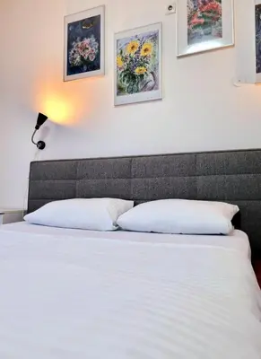 a bed in a room with paintings on the wall at Rooms Villa Luigi in Pančevo