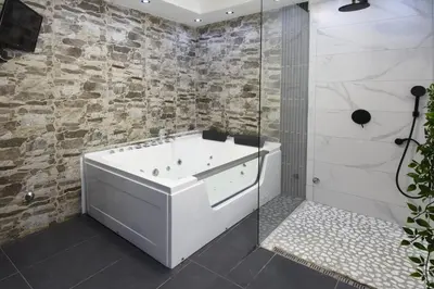 a bathroom with a white tub and a stone wall at TASOS in Belgrade