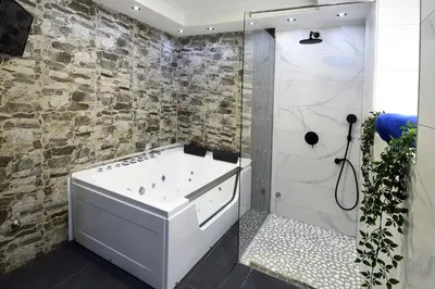 a bathroom with a white tub and a stone wall at TASOS in Belgrade